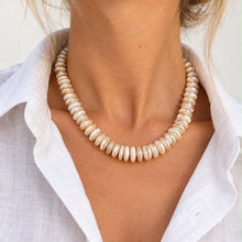 Load image into Gallery viewer, A close-up of a model wearing a chunky collar necklace made of small, irregular cream-colored beads, paired with a white linen button-down shirt.